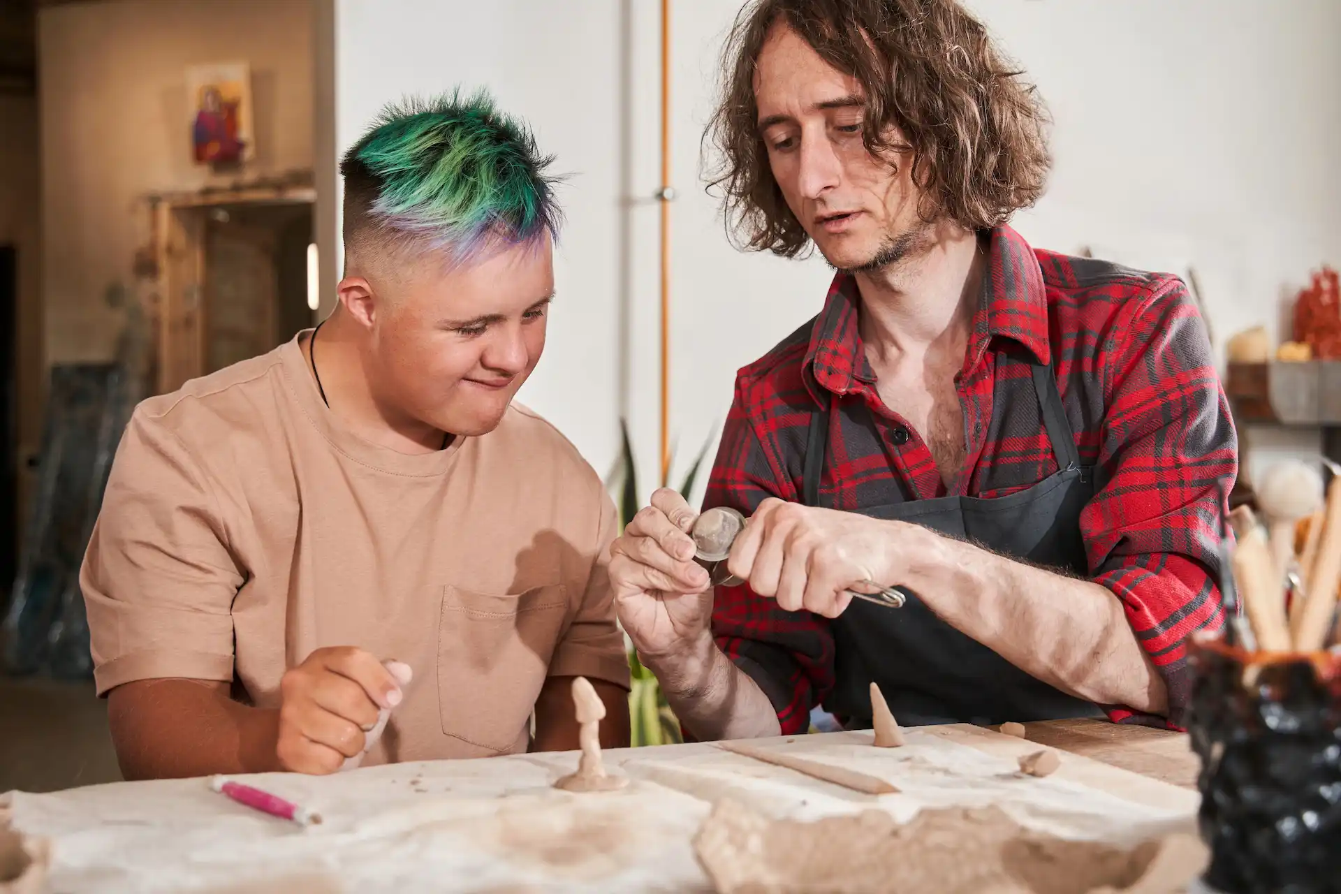 adult with disabilty working with clay with caretaker